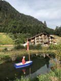 Vue de l'hôtel en été avec en premier plan petite barque avec un manequin sur un petit étang