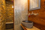 Salle de bains avec vasque en pierre, sous-vasque en bois, murs en pierre de la douche