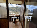 Vue sur le petit balcon depuis l'intérieur de l'appartement, table, chaise et Mt de Grange en arrière plan