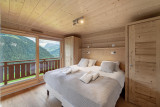 Chambre double avec grande baie vitrée donnant accès au balcon et vue sur la montagne