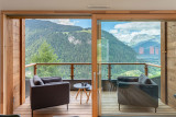 Balcon avec fauteuils, table basse, vue panoramique sur les montagnes et le village