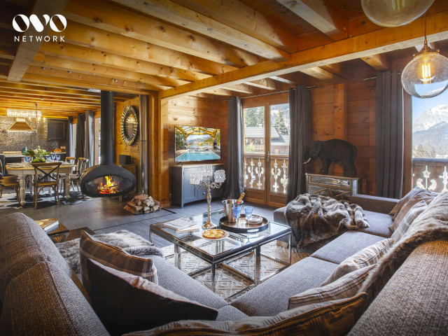 Salon avec  grand canapé, cheminée, baie vitrée donnant accès au balcon