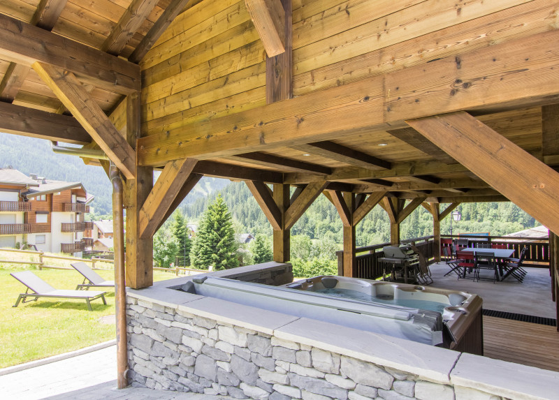 Terrasse couverte avec bain à remouds, barbecue et espace repas