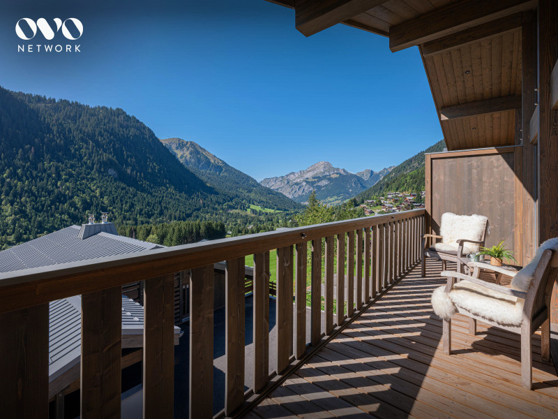 Balcon avec salon de jardin en été, vue sur la vallée et les montagnes